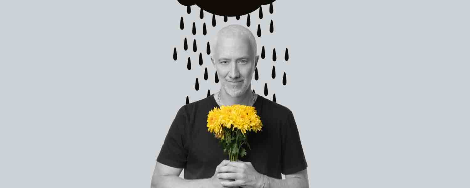 Hombre agarrando unas flores amarillas y arriba de su cabeza hay una nube y gotas de lluvia